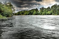 阴沉的天空下，郁郁葱葱的树木环绕着风景优美的河景