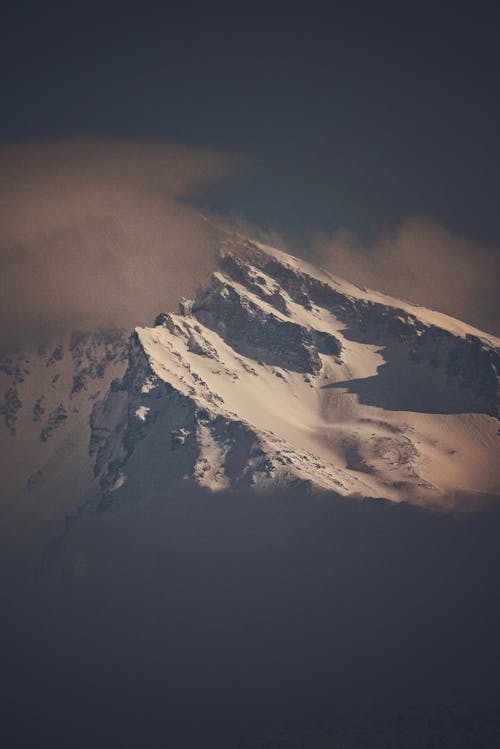 Snowy mountain peak against cloudy sky