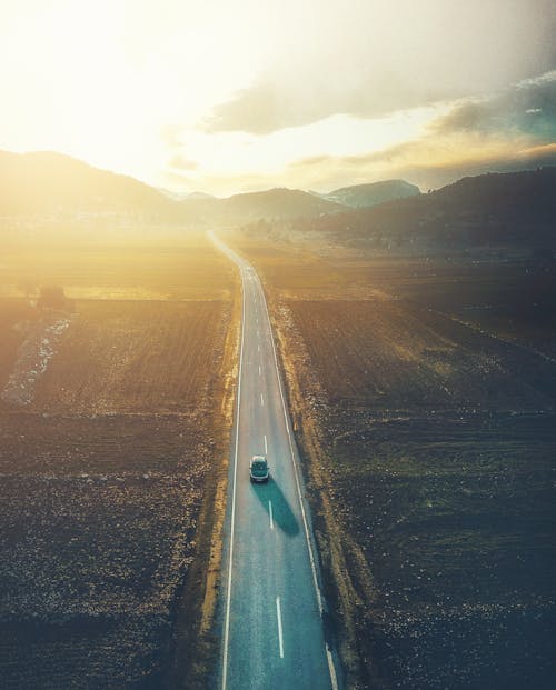 Vehicle driving on highway in mountainous countryside at sundown