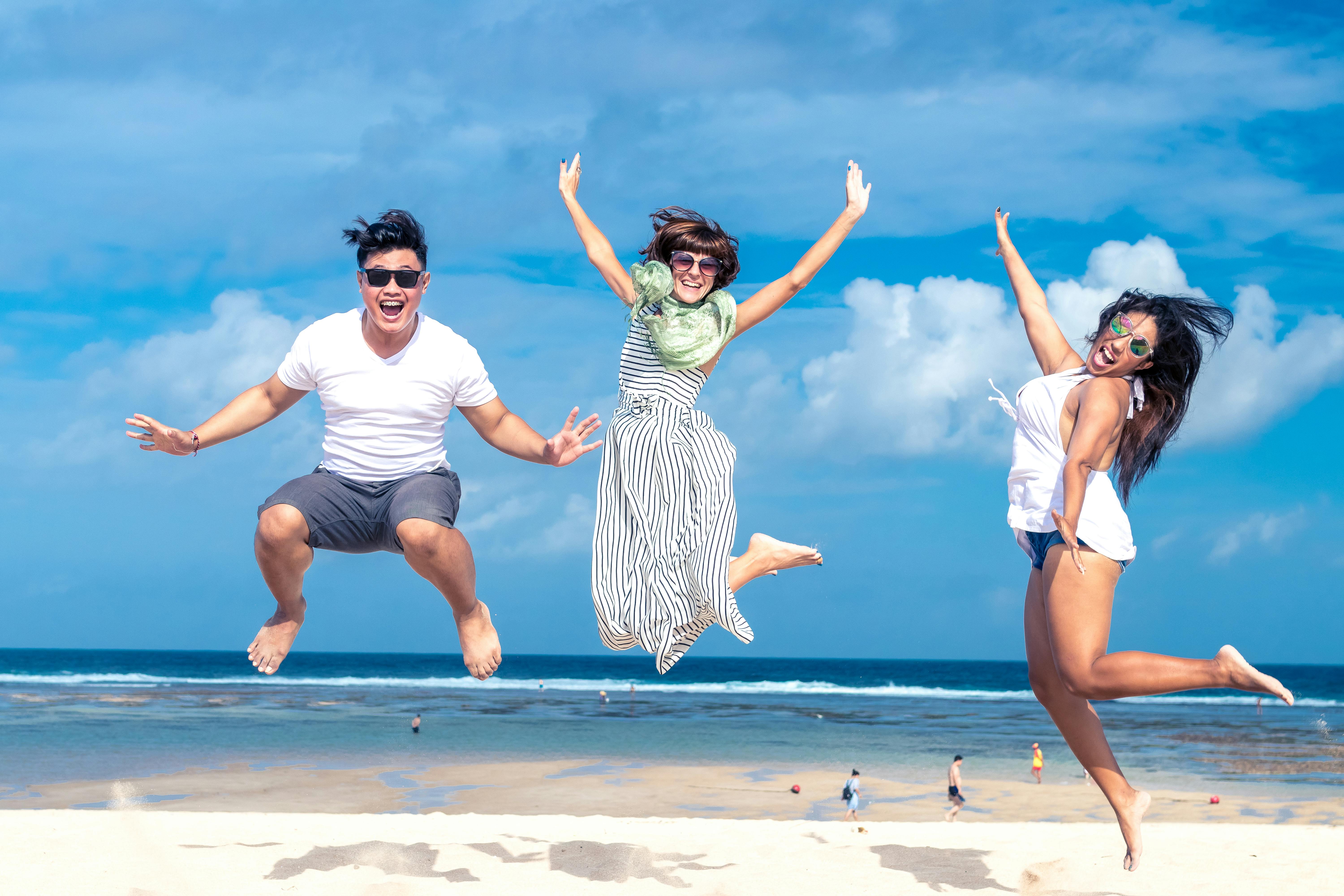 Man and women jumping on seashore.  | Photo: Pexels