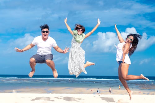 Free Woman and Man Jumping on Seashore Stock Photo