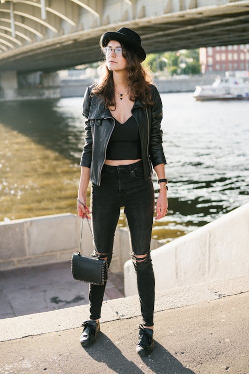 Young woman in black outfit against city river · Free Stock Photo
