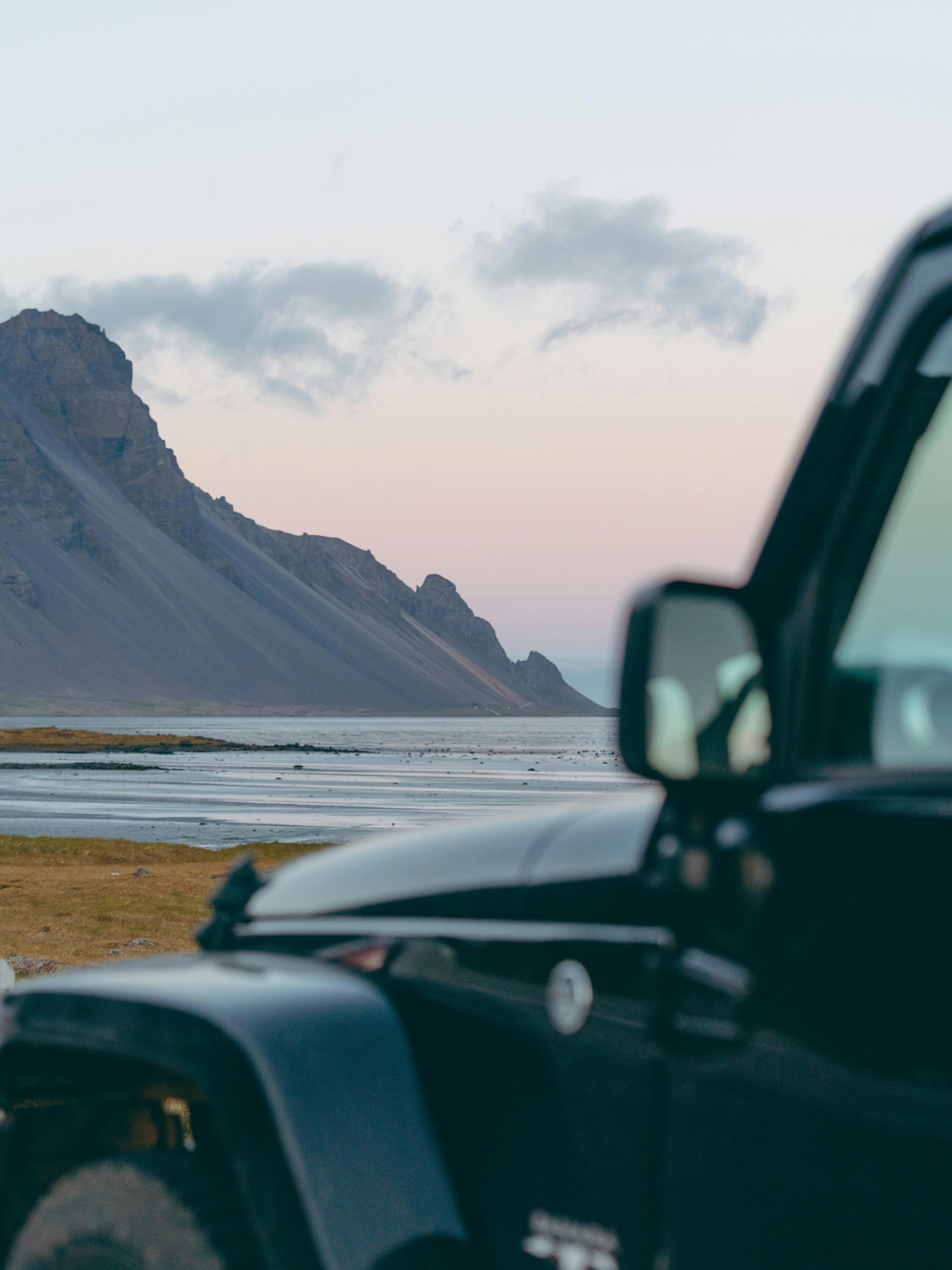 A rugged jeep parked near the beautiful Stokksnes mountains on an Icelandic adventure trek.