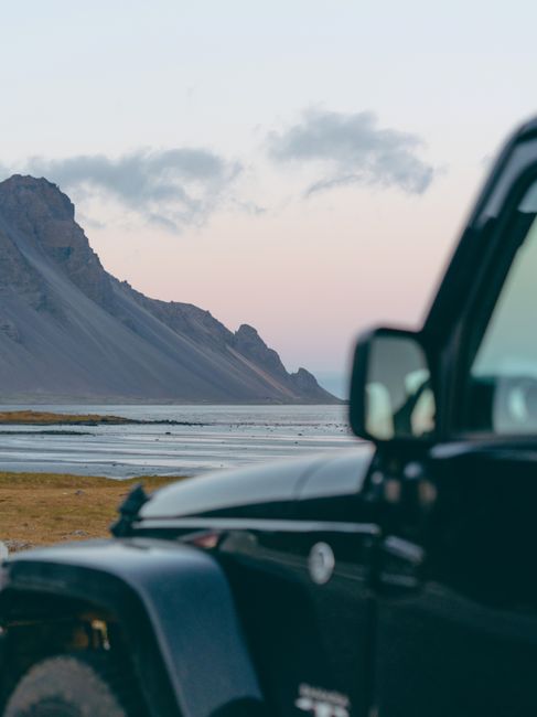 A rugged jeep parked near the beautiful Stokksnes mountains on an Icelandic adventure trek.