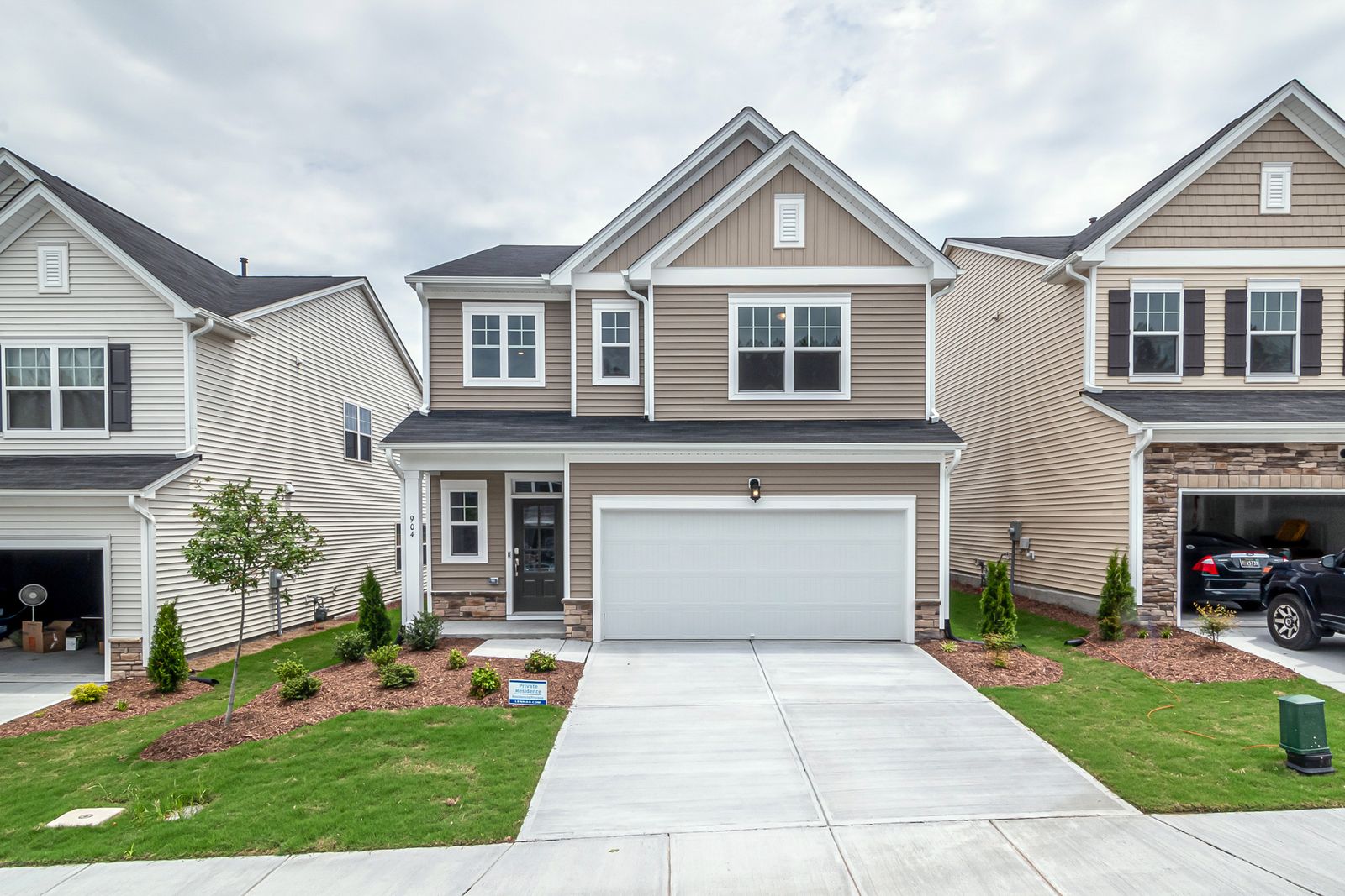 Two-story home with tan siding, stone accents, an attached garage, and younger landscaping on a well-planned street, Ashwood Pointe, Naperville IL