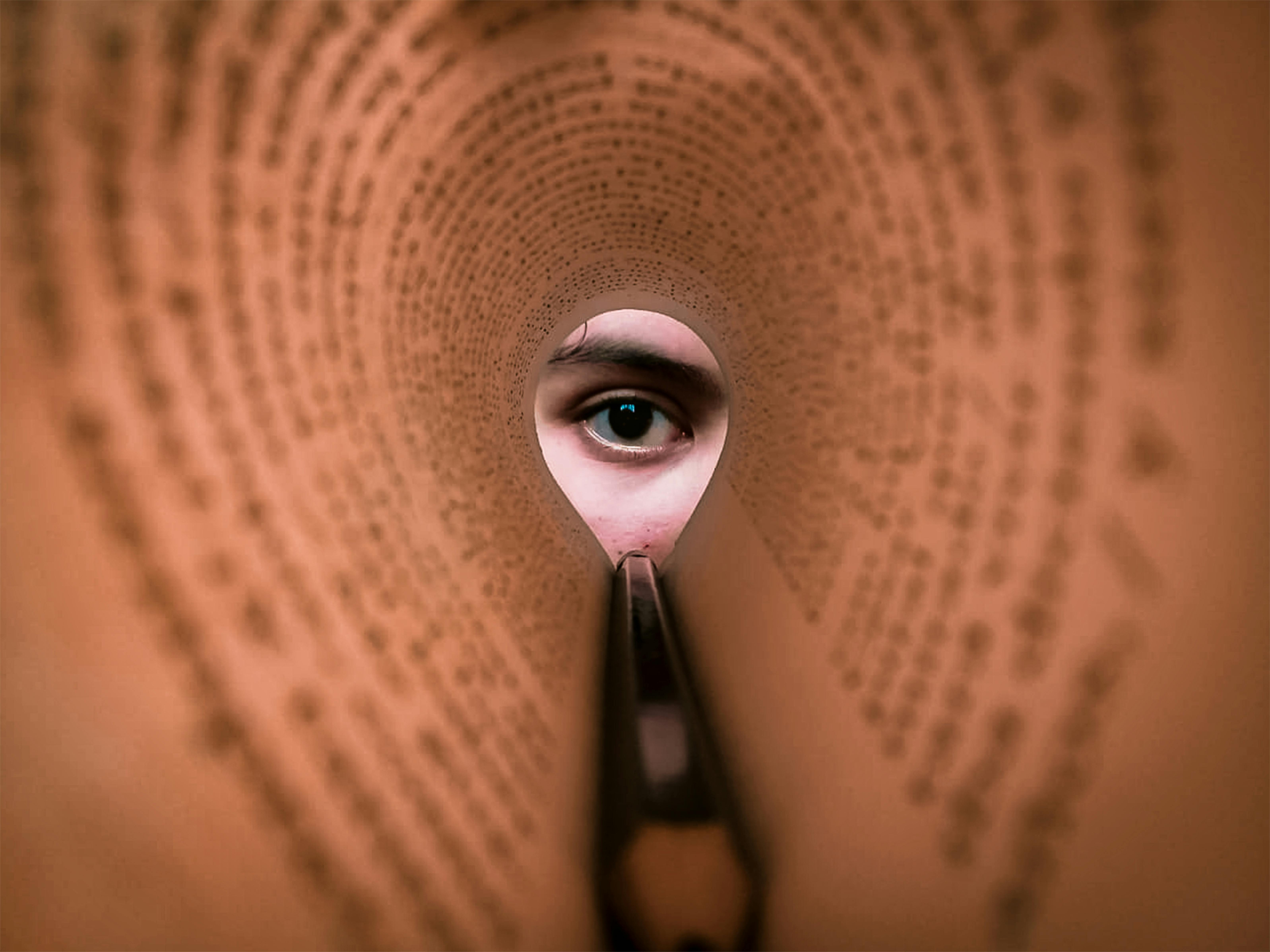 A person's eye looking through a rolled book page, creating a unique viewpoint.