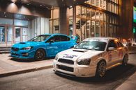 Modern fast sport cars with contemporary design on asphalt road on illuminated city street near glass building in urban area