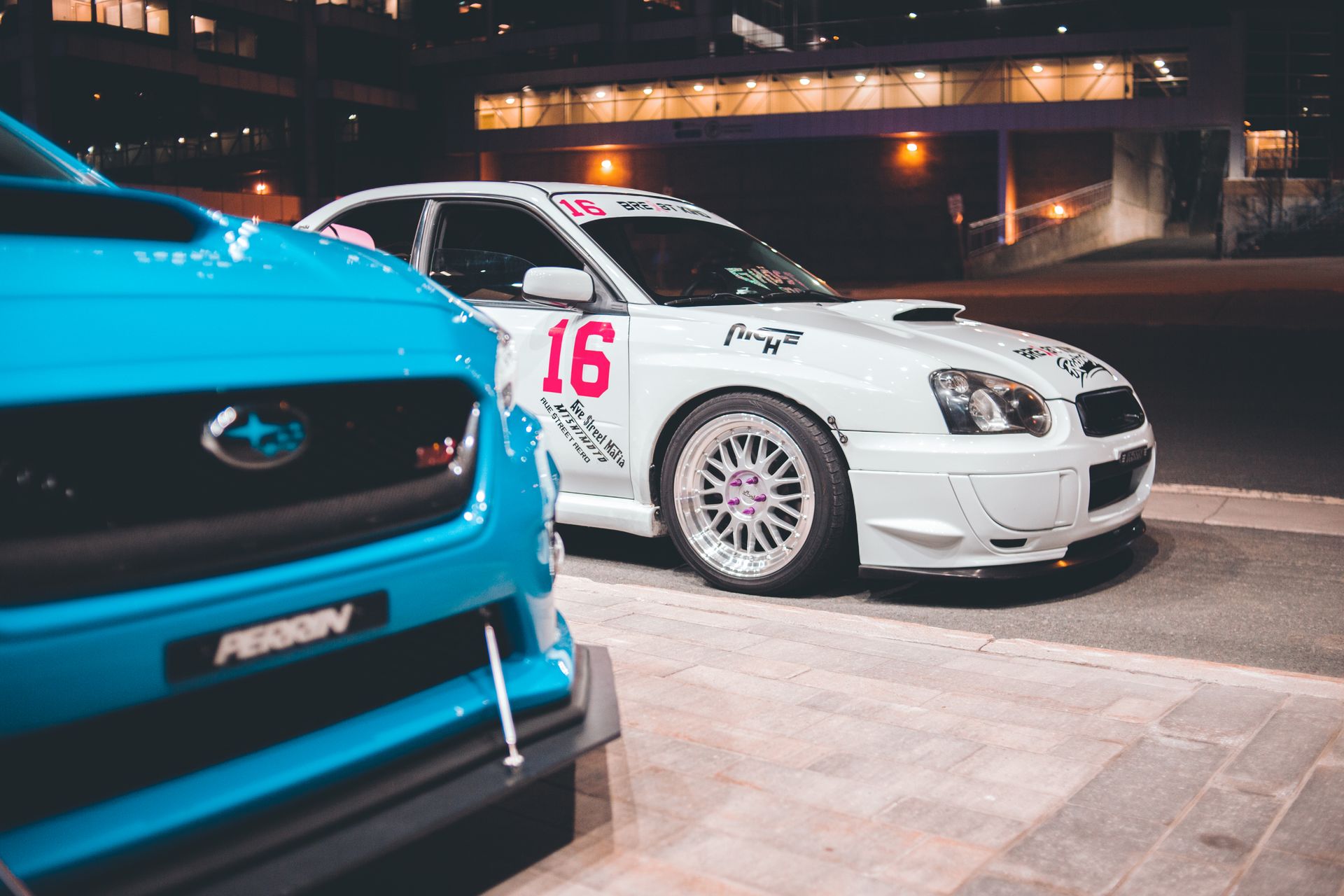 Stylish modern race cars with trendy tuning parked on illuminated city street at night