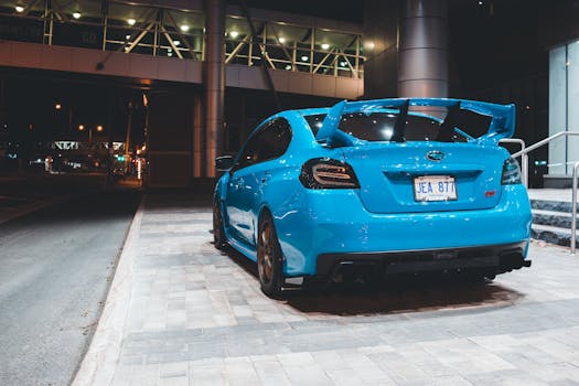 A vibrant blue sports car parked at night in a modern urban environment, showcasing its sleek design.