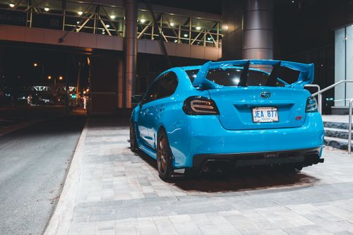 Free Trunk of new modern shiny blue car with spoiler parked on pavement near footbridge on city street at night Stock Photo