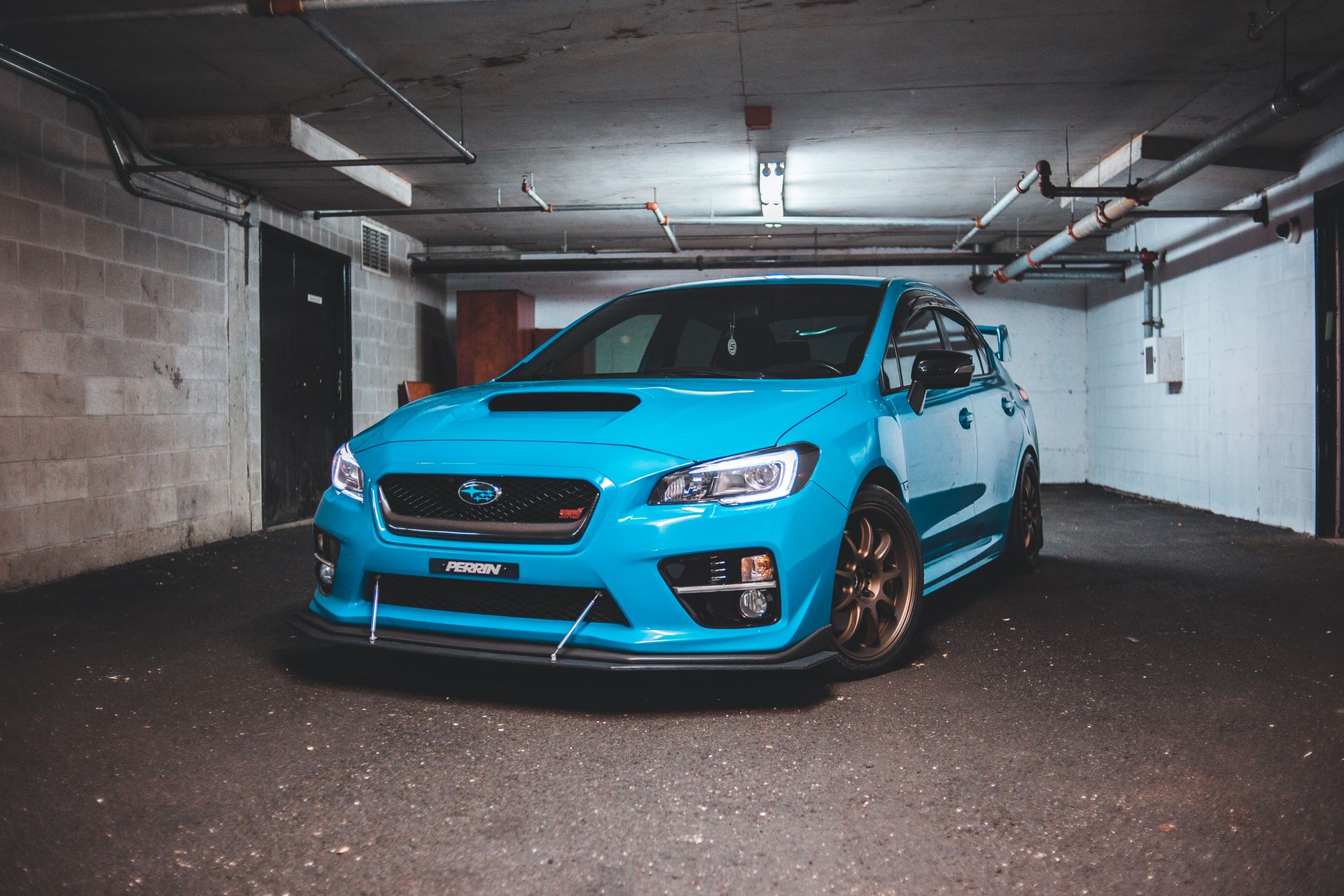 Trendy blue tuned sports car with glowing headlights and spoiler parked in garage