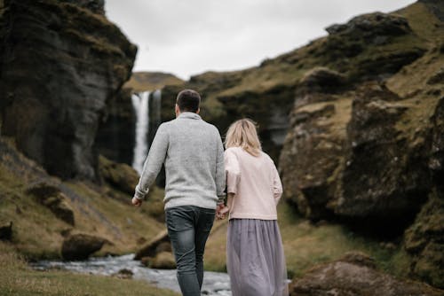 Anonymous young couple walking near hidden Kvernufoss waterfall in Iceland