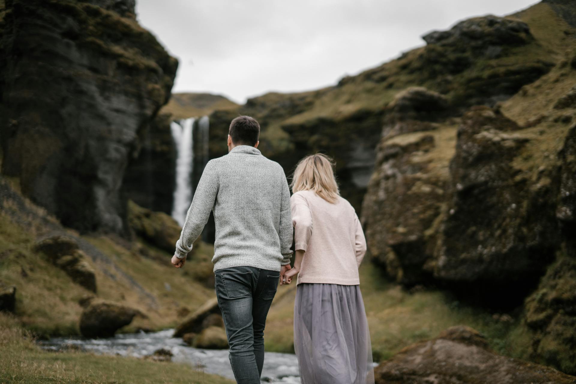 Anoniem jong stel loopt langs de verborgen Kvernufoss-waterval in IJsland