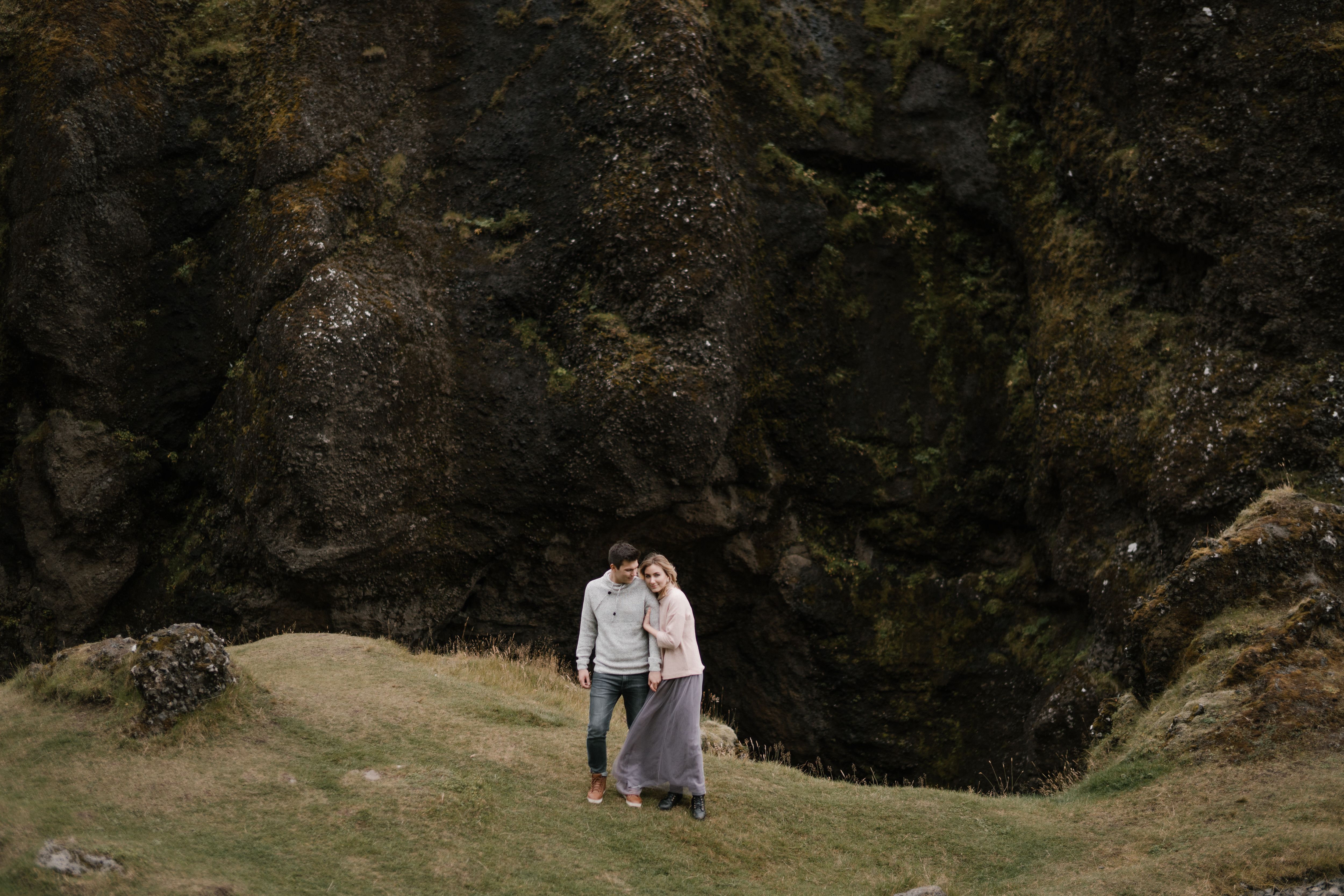 From above of cuddling young couple standing together on edge of huge rocky cliff
