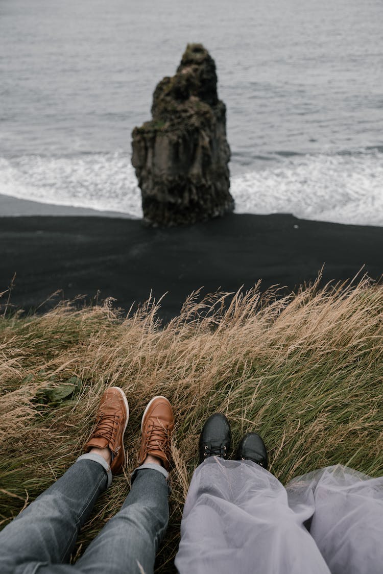 Unrecognizable Couple Lying In Grass On Reynisfjara Beach In Iceland