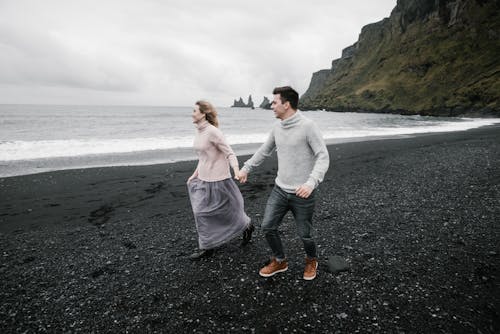 Cheerful couple having romantic date on beach on chilly day