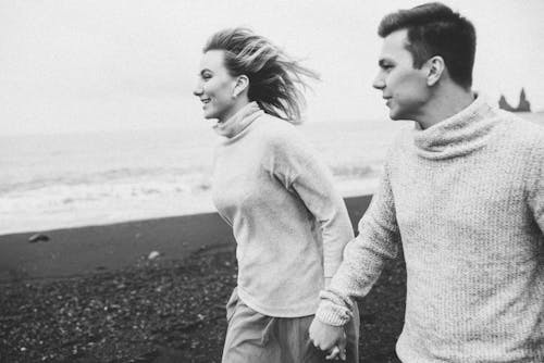 Positive married couple exploring seashore at weekend