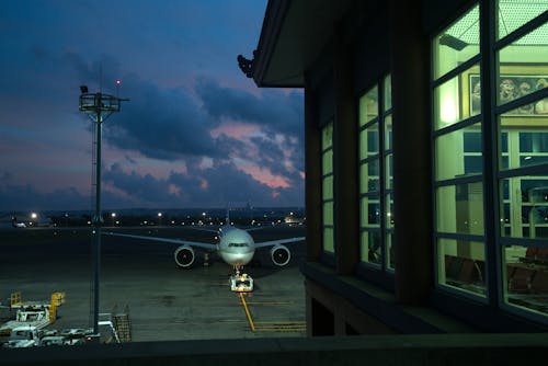 Modern plane parking on stand near assigned gate in modern airport terminal at night