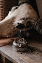 Round wooden ashtray with metal design full of cigarette stubs and horned animal skull on dusty wooden table