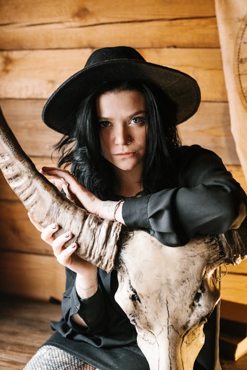 Stylish young lady in black hat with horned animal skull
