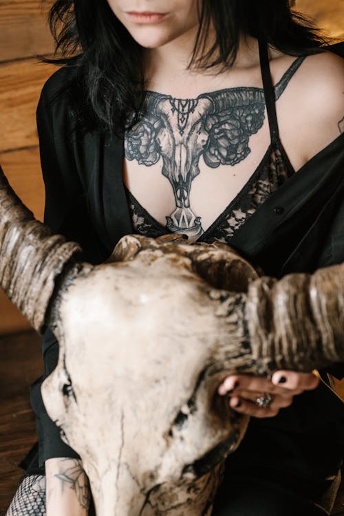 Crop woman with cool tattoos and animal skull