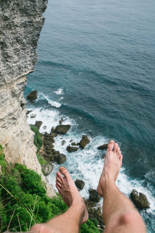 Anonymous man admiring stormy sea from rocky cliff