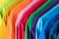 Closeup of multicolored vibrant cotton t shirts hanging in row in modern wardrobe