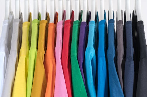 Free Selection of colorful bright fashionable t shirts hanging on rack in store against white background Stock Photo