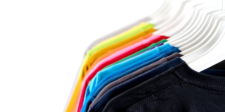 Trendy Multicolored Garments Hanging On Rack Against White Background