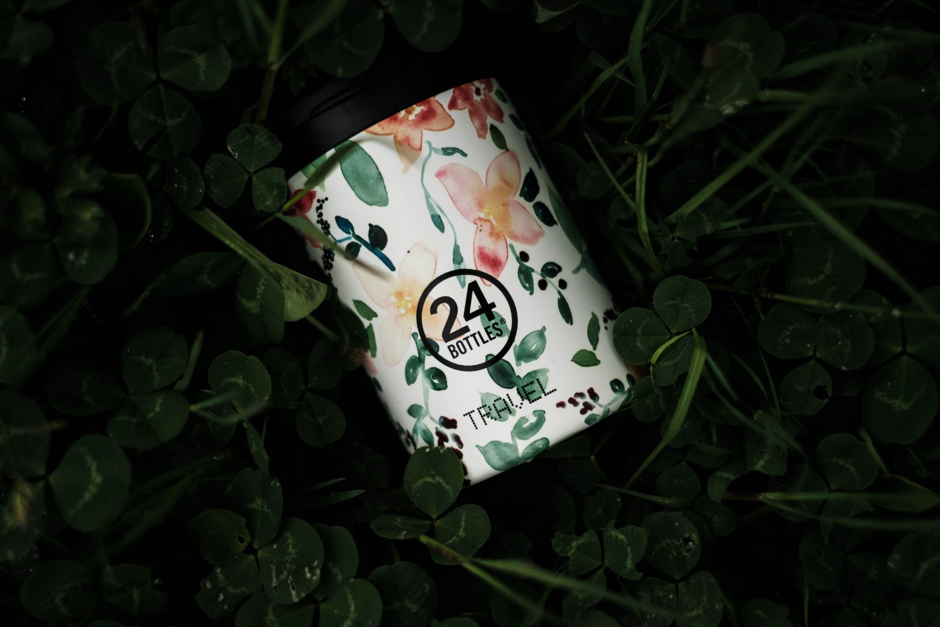 A floral-patterned eco-friendly water bottle nestled in lush green foliage.