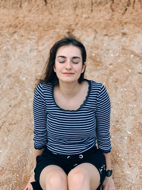 Delighted young woman sitting on stony ground