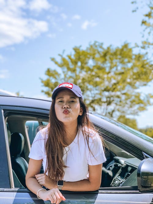 Positive young woman blowing kiss sitting in auto