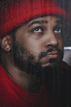 雨纹窗户后，一个穿红衣男人的情感肖像，唤起了内省