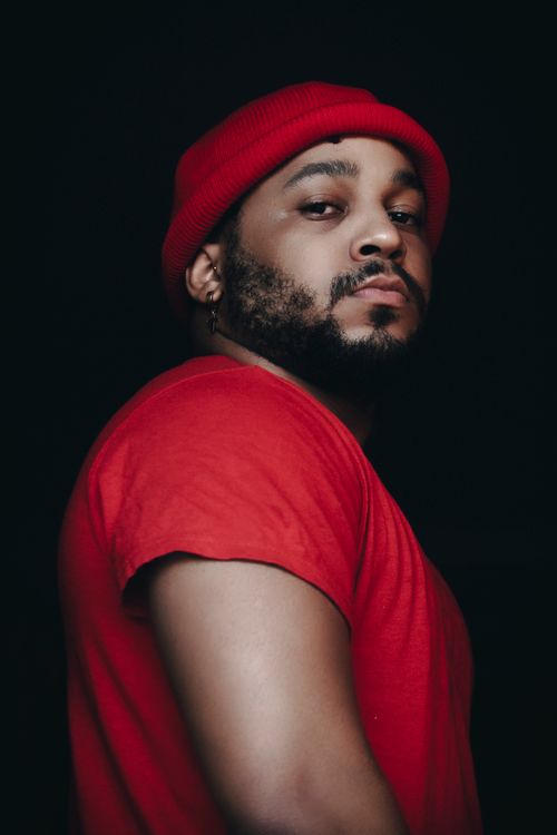 Free Close-up portrait of a bearded man wearing a red beanie and shirt on a dark background. Stock Photo
