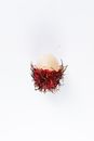 Fresh ripe exotic rambutan half peeled from red skin placed on white background