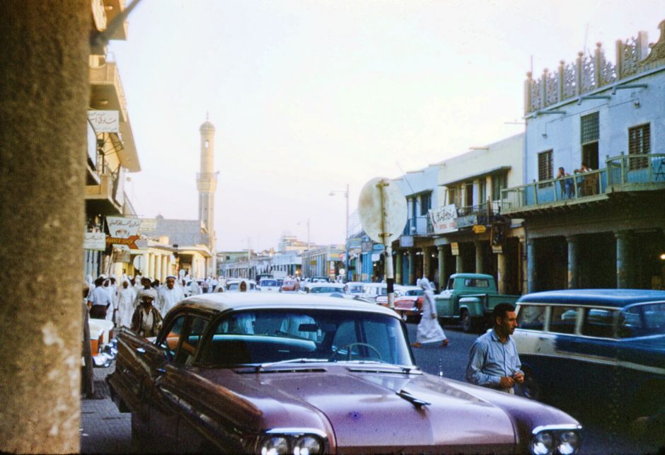Cars driving on a multi-lane road in a Saudi Arabian city like Riyadh, with modern architecture in the background.