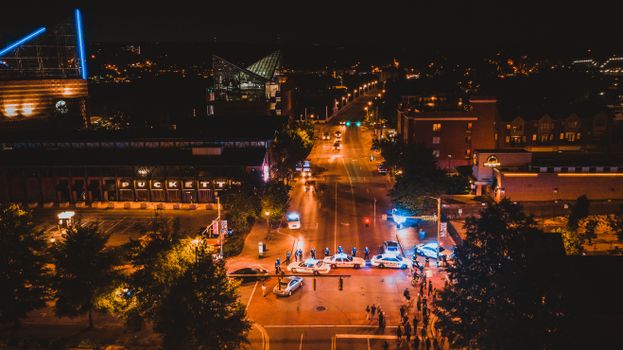 Drone view of glowing lights of city streets with police cars at night