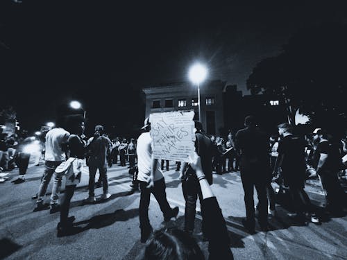 Grayscale Photo of a Protester Holding a Sign