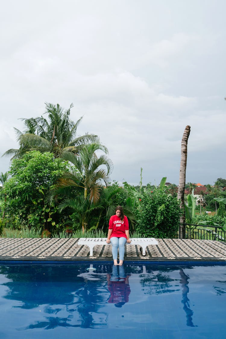 Woman Dipping Feet In Swimming Pool Water At Resort