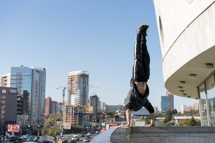 Daredevil Thrill Seeker Doing Handstand On Roof Edge In Modern City