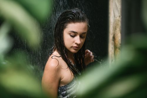 Free Young gorgeous long haired brunette enjoying shower at spa resort full of vibrant tropical greenery Stock Photo