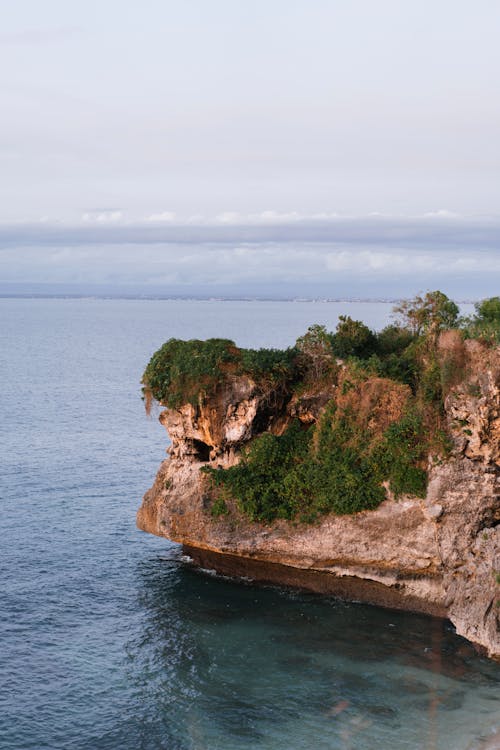 Famous limestone cliff of Balangan Beach in Bali grown with greenery and overlooking calm blue Indian ocean