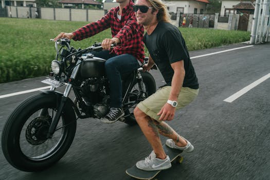 Two friends enjoy an adventurous ride in the countryside—one on a motorcycle, the other on a skateboard.