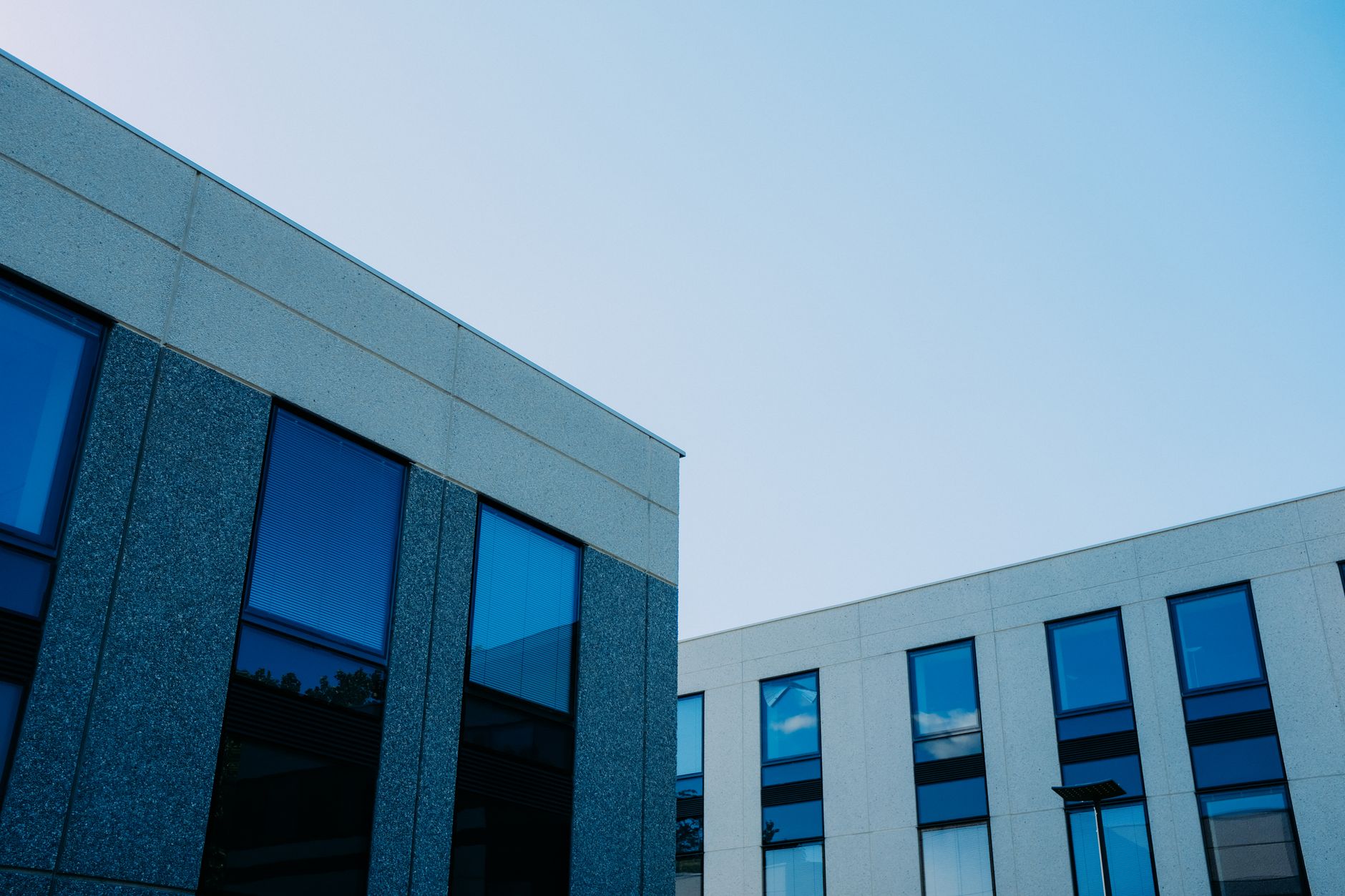 From below of contemporary office buildings with reflection in windows located in city