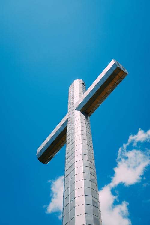 From below of metal cross located on top of mountain in France at daytime
