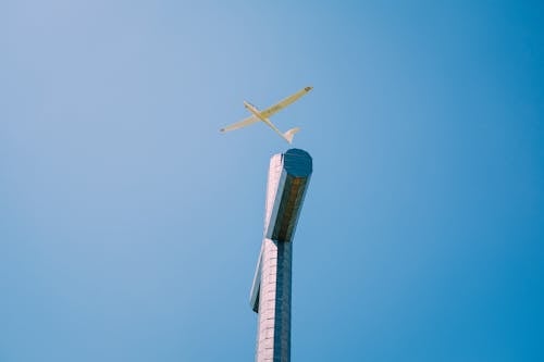 Airplane flying under cross in sky