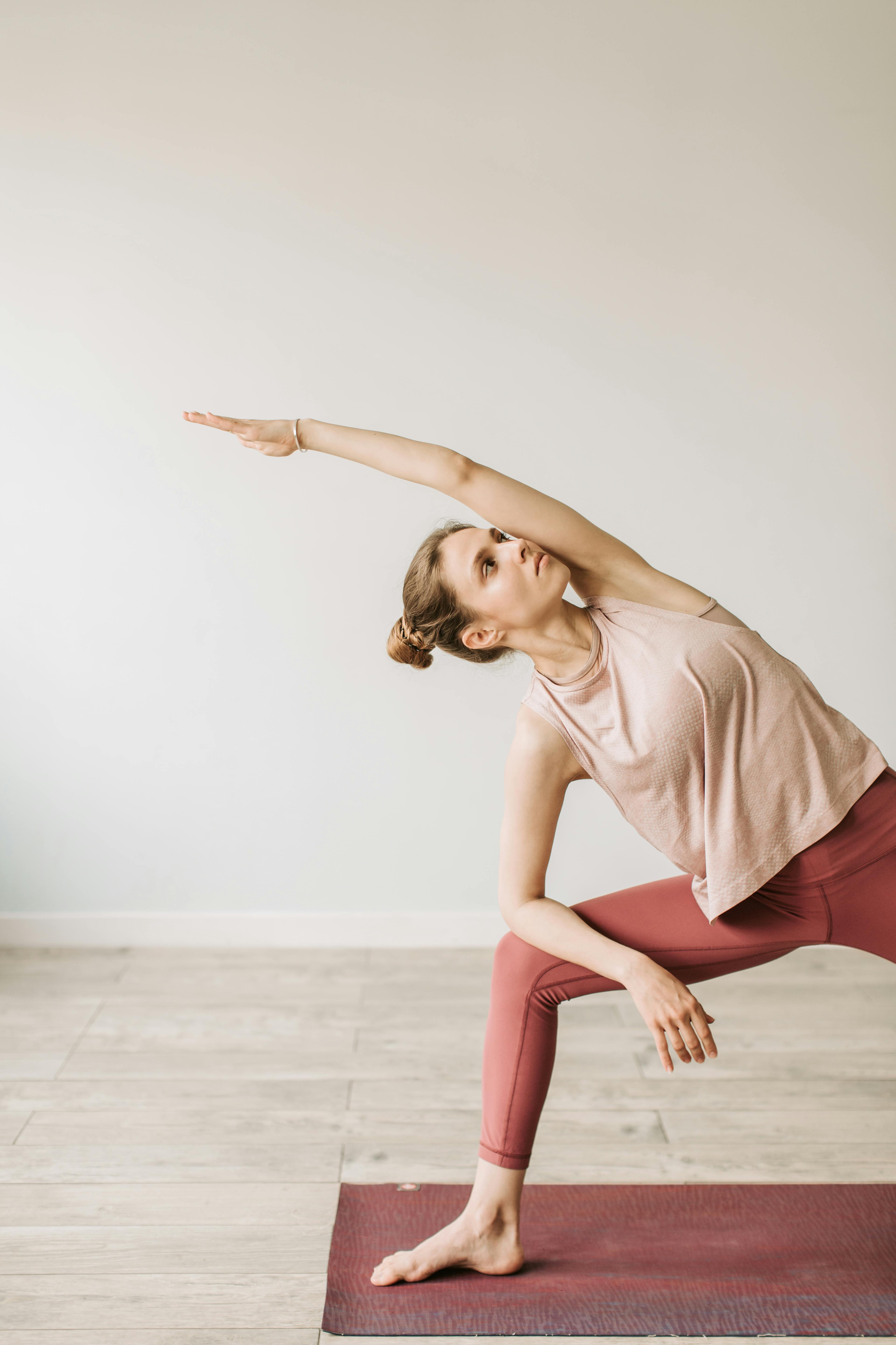 Flexibility exercises. Athletic young woman doing yoga on mat, stretching  her legs during home Stock Photo by Prostock-studio