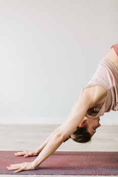 Young woman in downward dog position on yoga mat, indoor setting.