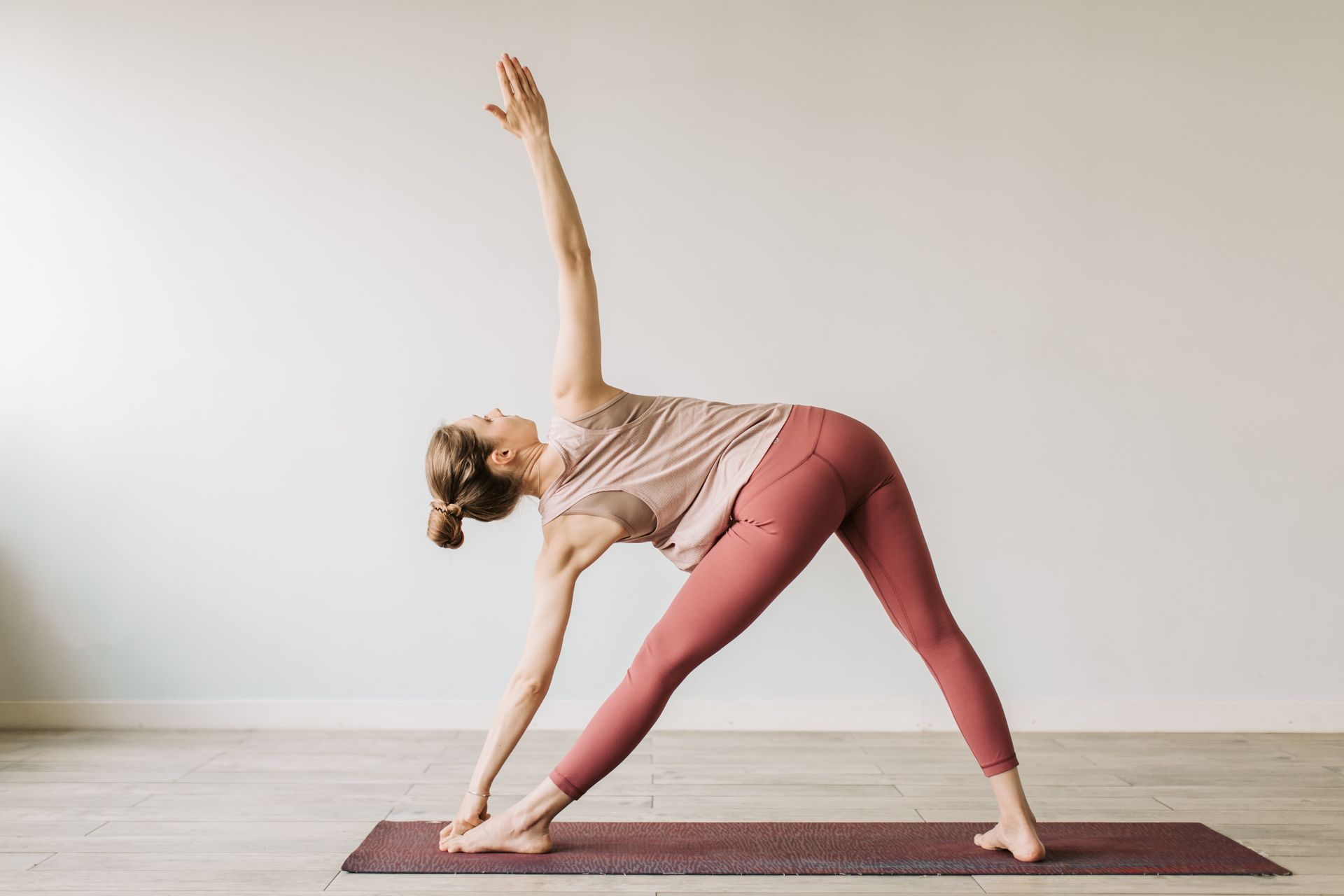 A woman performing the yoga triangle pose indoors, showcasing flexibility and wellness.