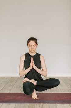 Adult woman meditating indoors in a peaceful and serene environment on a yoga mat.